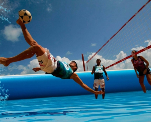 Juagador de waterfootvolley haciendo una tijereta en una piscina deportiva profesional
